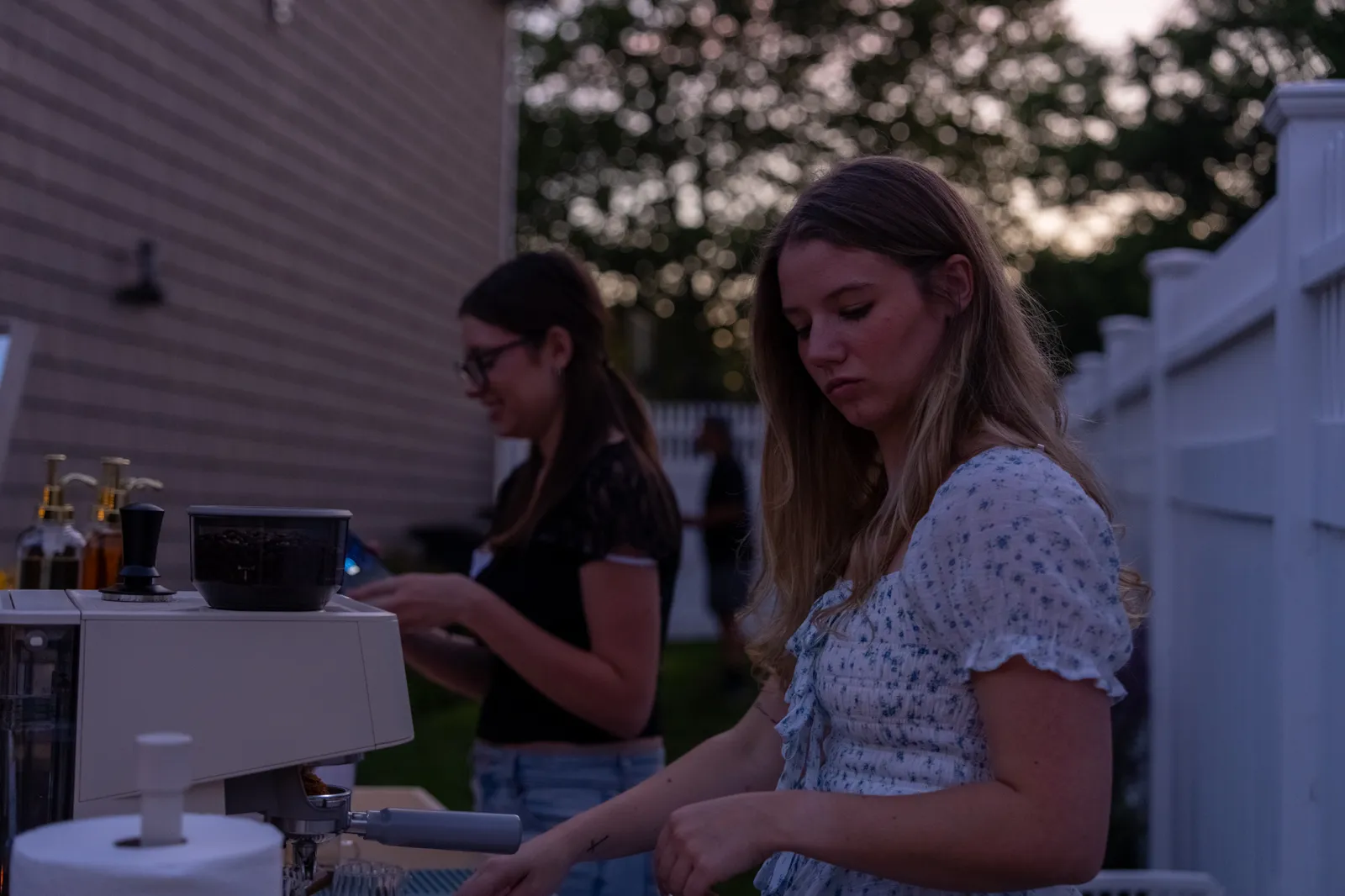 Two staff work the cart at golden hour, one tending the espresso machine.