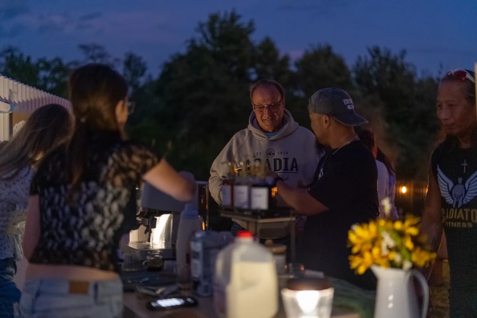 Guests gather at the cart at dusk, string lights glowing behind them.